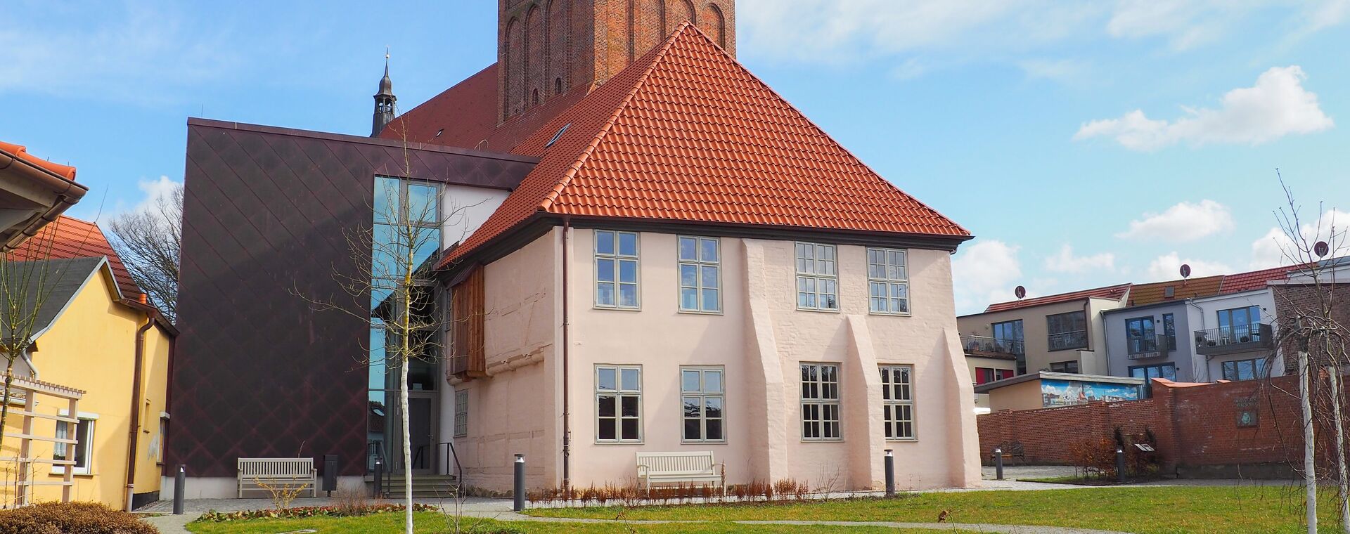 Ältester Profanbau Mecklenburg-Vorpommerns. Großes Haus mit Garten und Kirche im Hintergrund